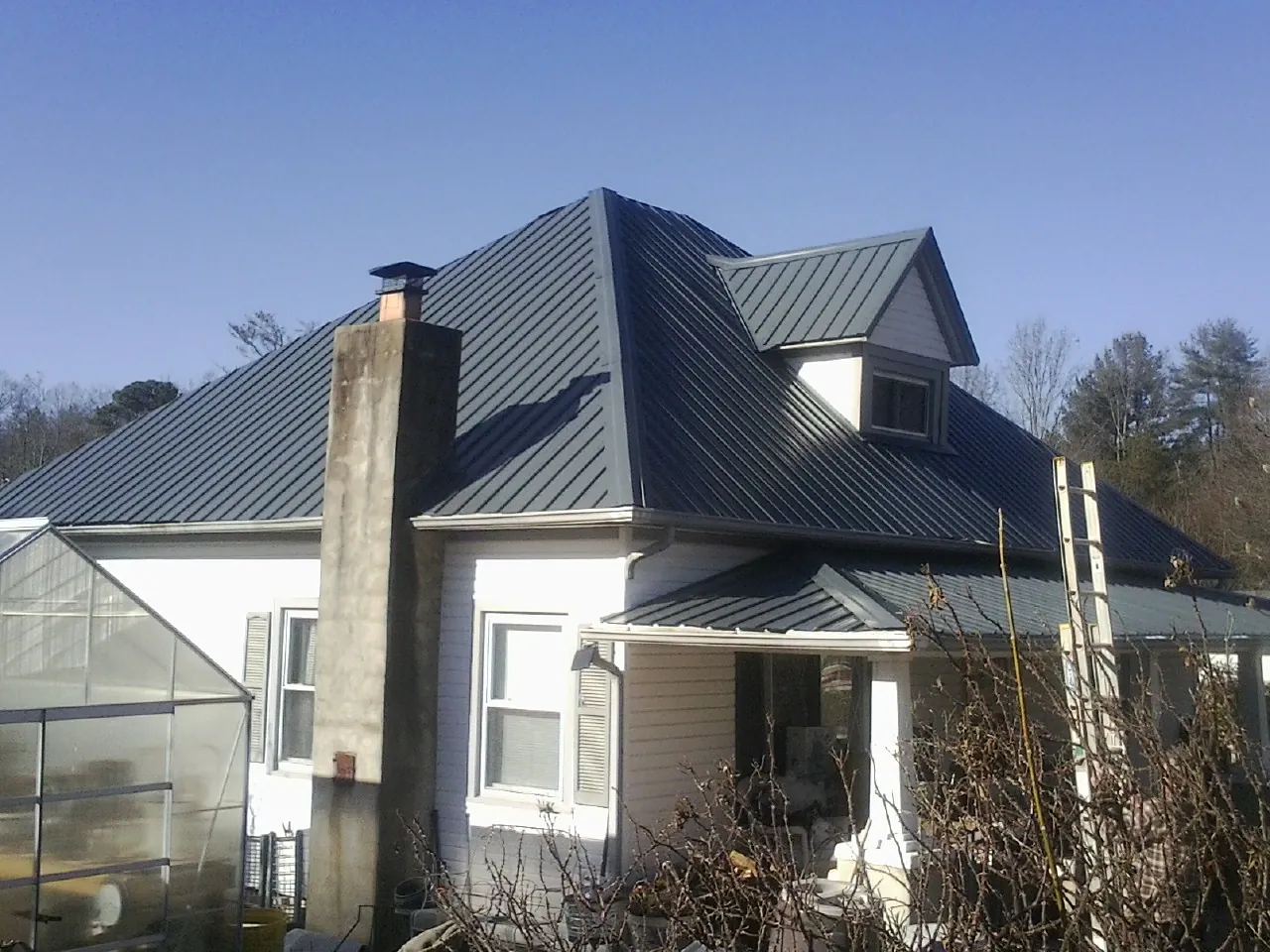 Dark blue standing seam metal roof on a white farmhouse with dormer — Slate & Tile Roof Repair by Roofing Brothers in Mount Hope