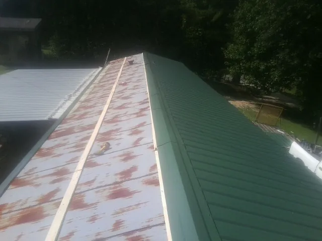 Old rusted panels beside newly installed green metal roofing — Wind Damage Roof Repair by Roofing Brothers in Mount Hope