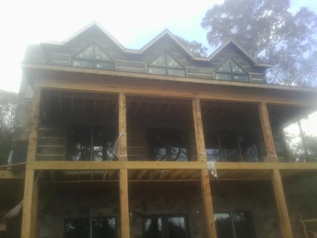 Dormers and porch framing on a large log home under construction — Roof Coating work by our crew in Mount Hope