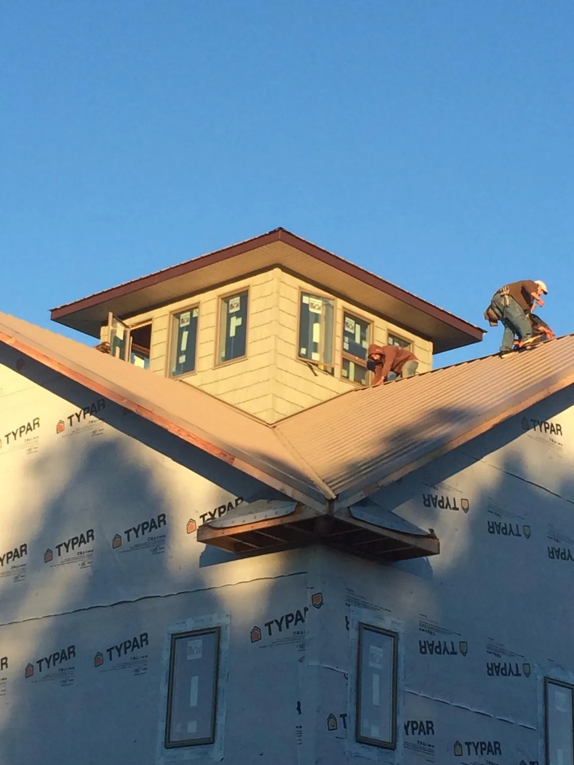 Roofers working around a rooftop cupola on a new metal roof at sunset — Roof Waterproofing in Mount Hope by Roofing Brothers